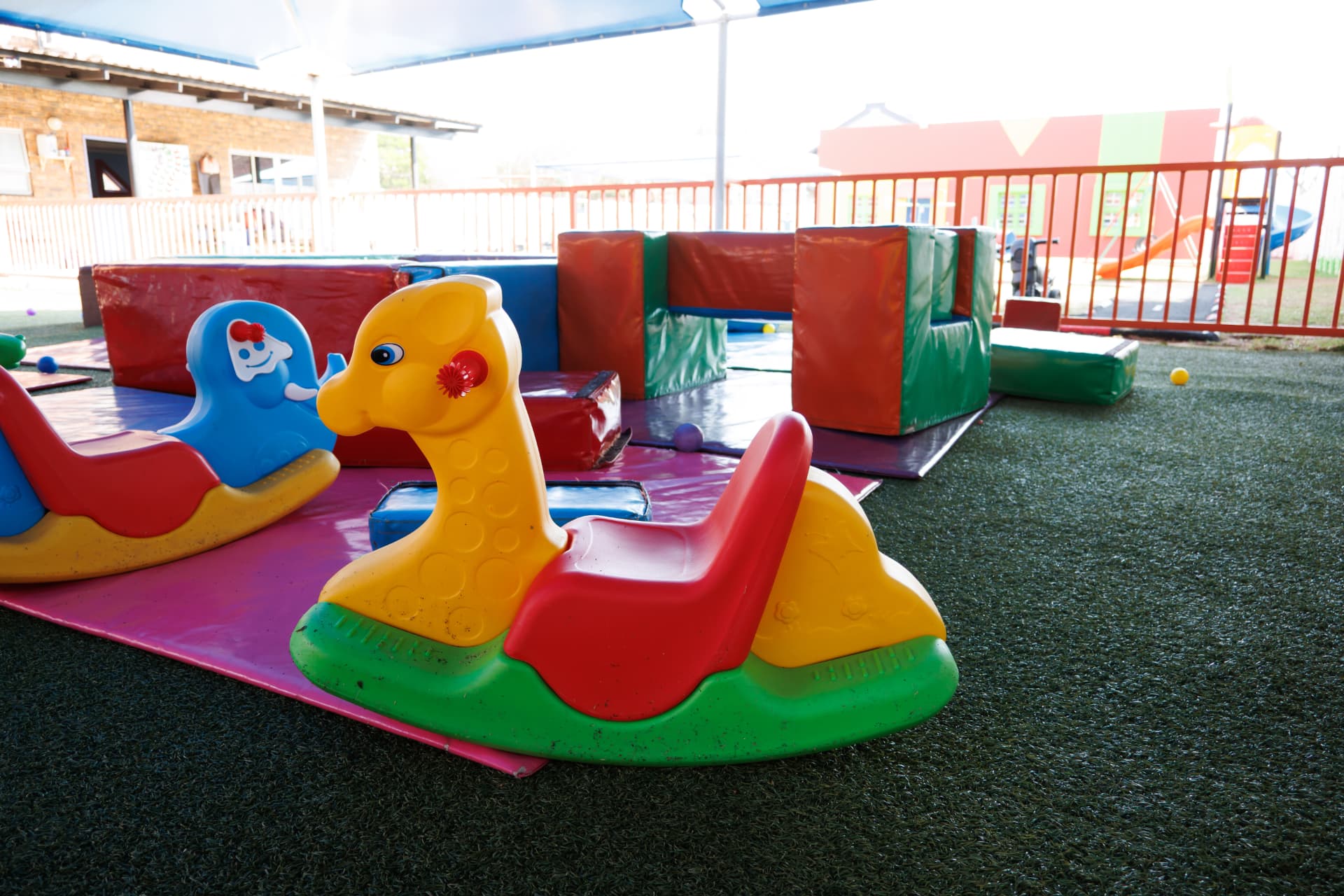 Colourful rocking toys and soft play blocks on the shaded turf area