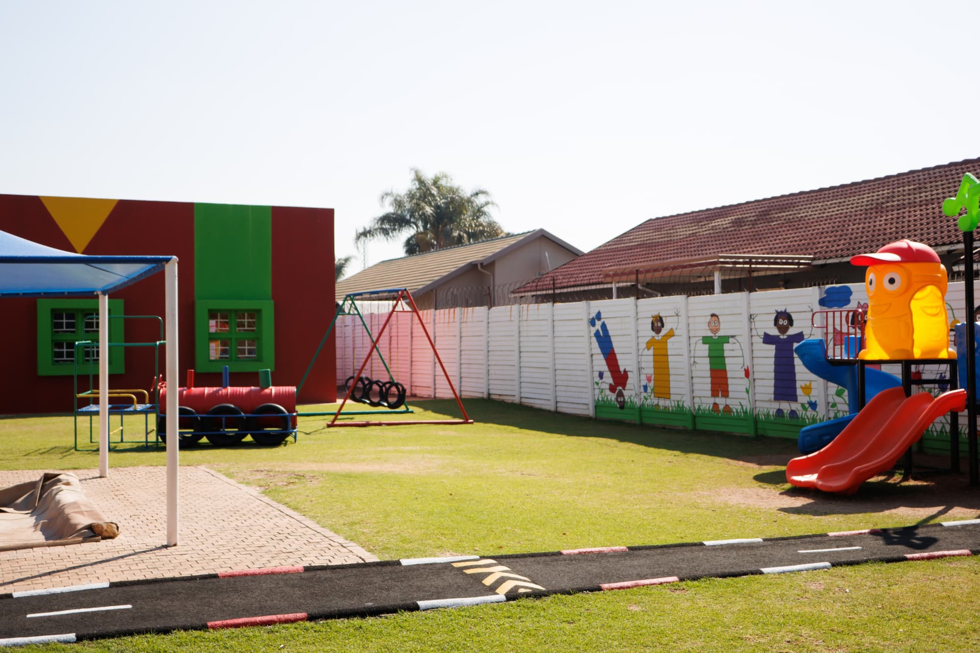 Play area with train, swings, slide and shaded space