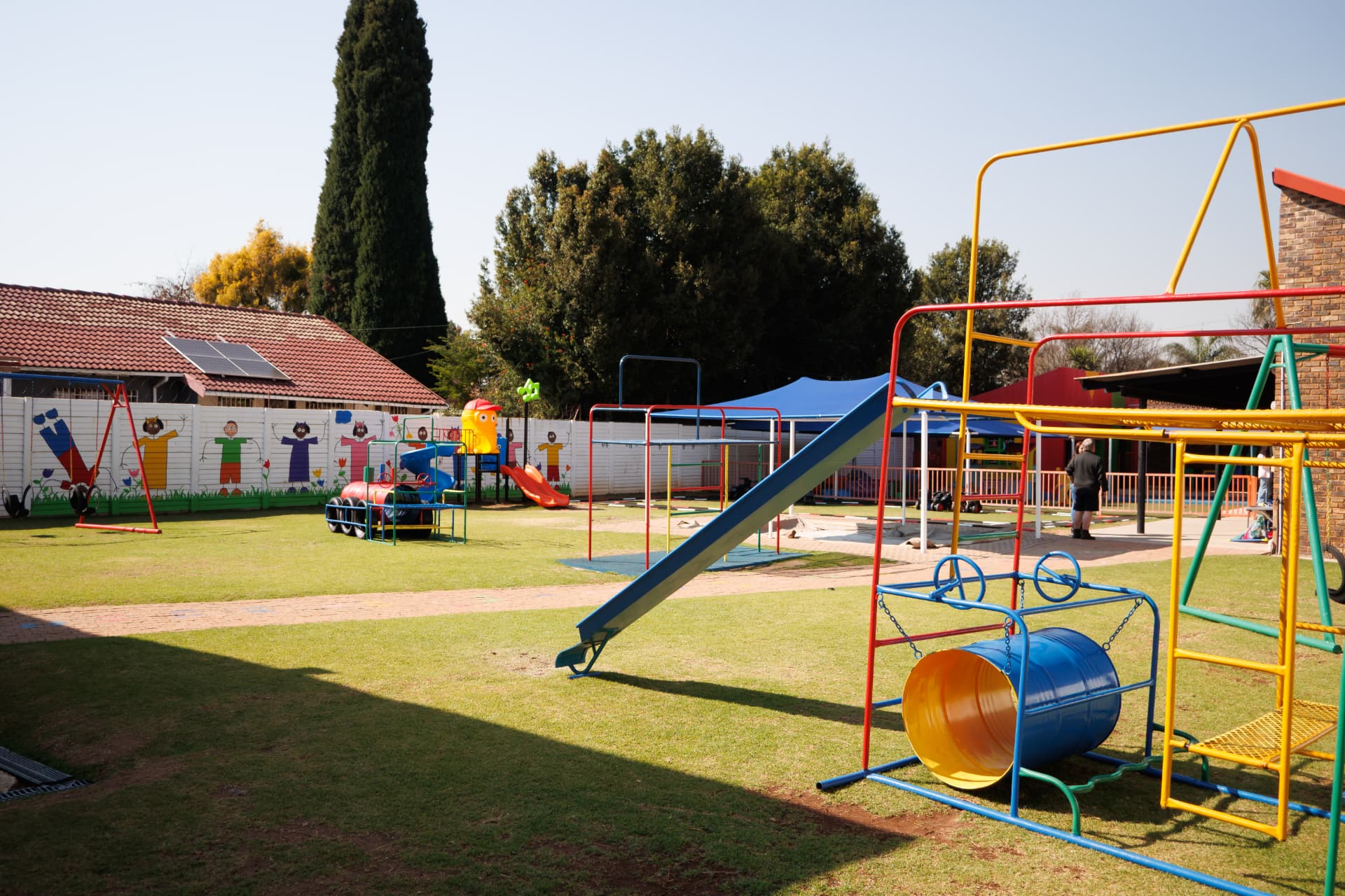 Wide view of the grass playground with jungle gyms, slides and swings