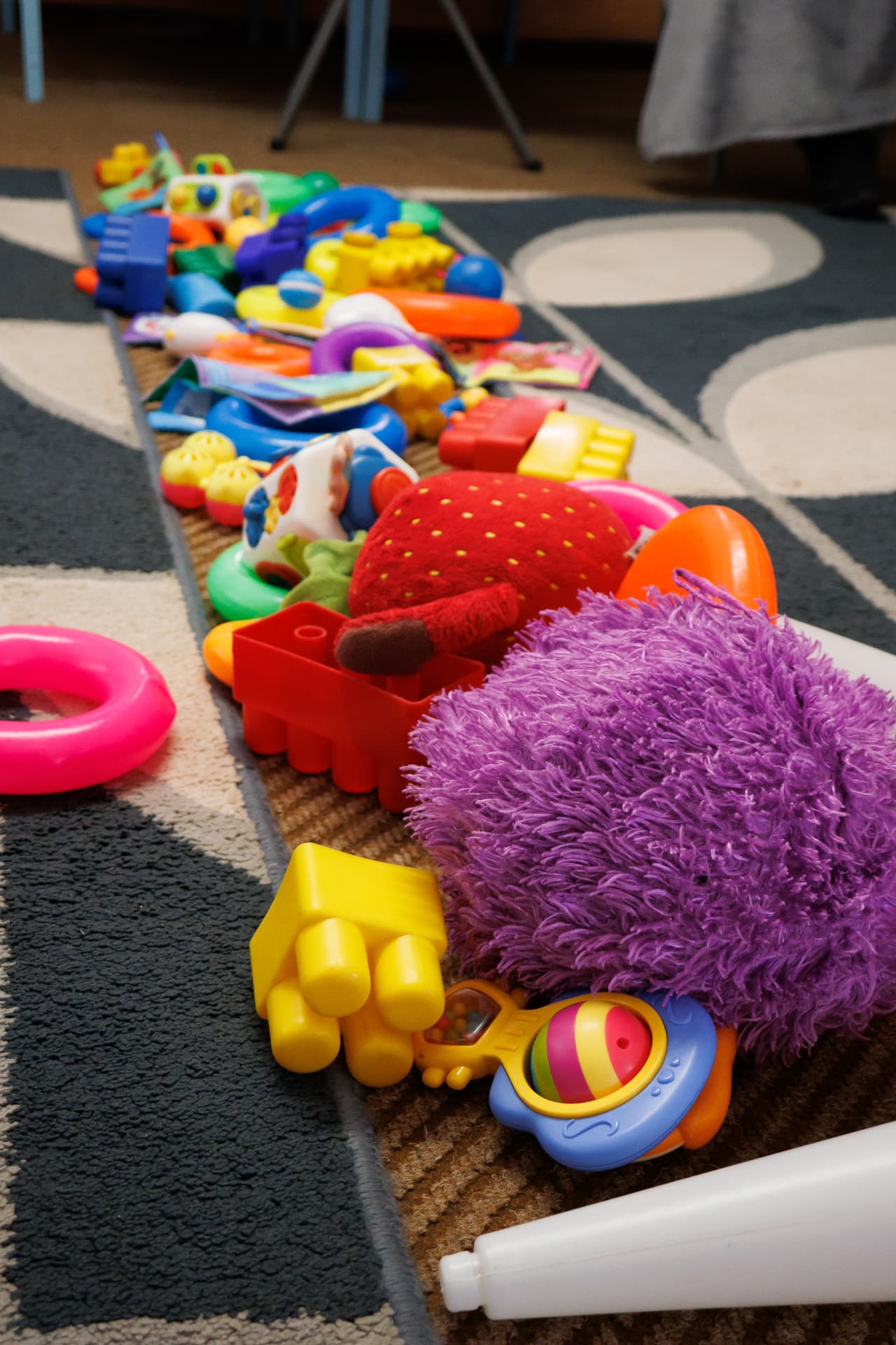 Row of colourful baby toys laid out on the classroom mat