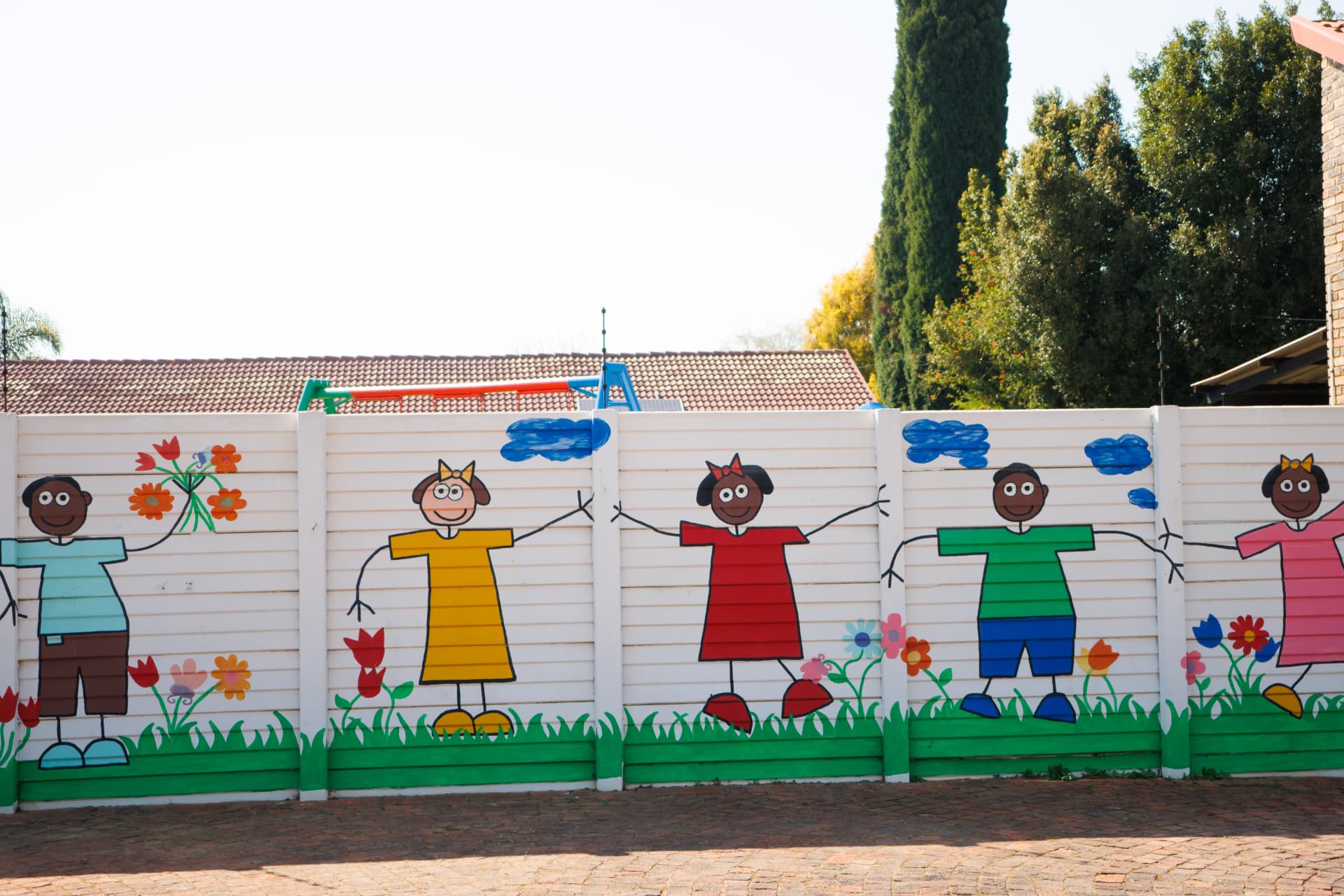 Painted wall mural of children holding hands among flowers