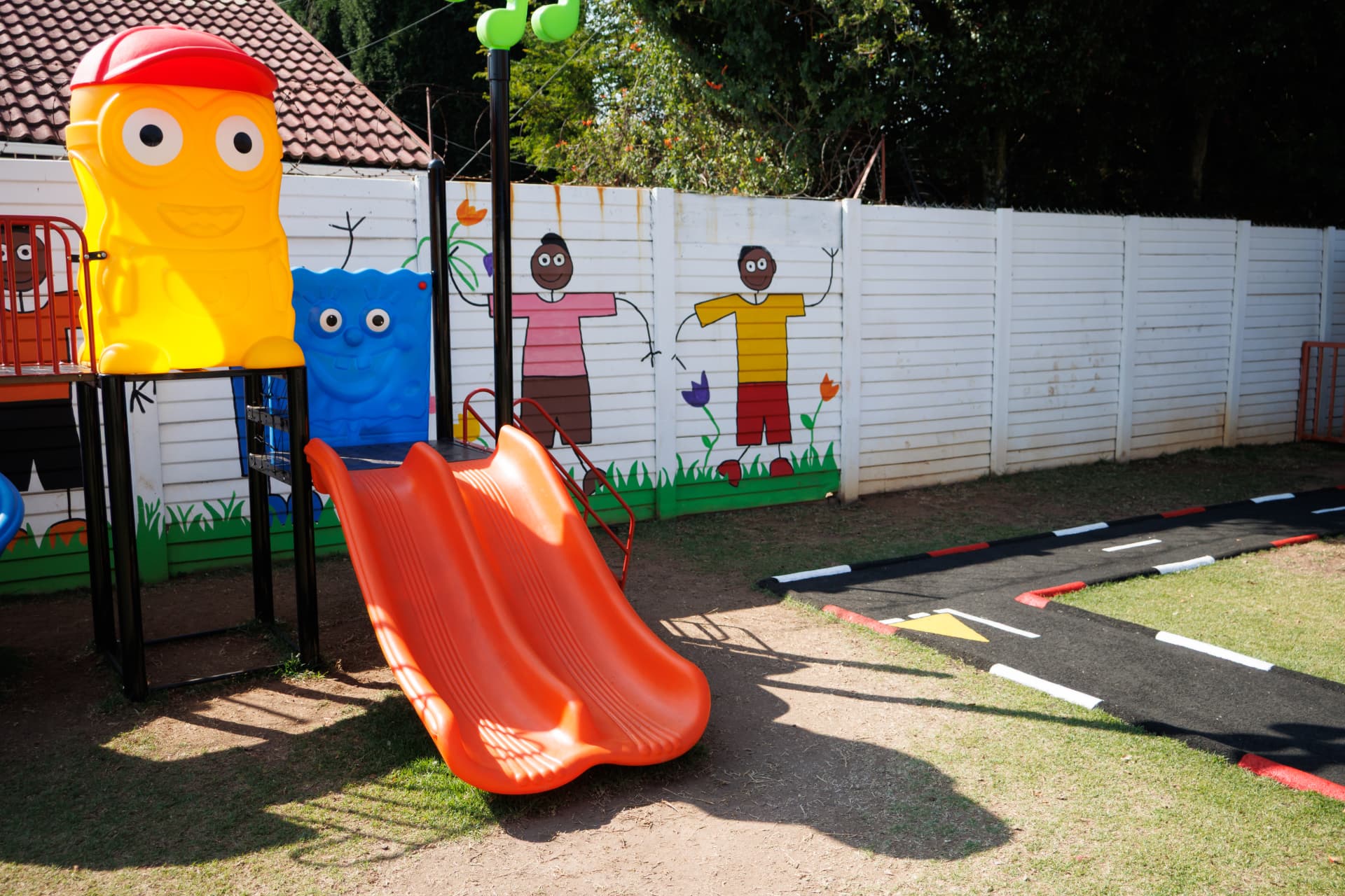 Orange slide and jungle gym next to the painted mural fence