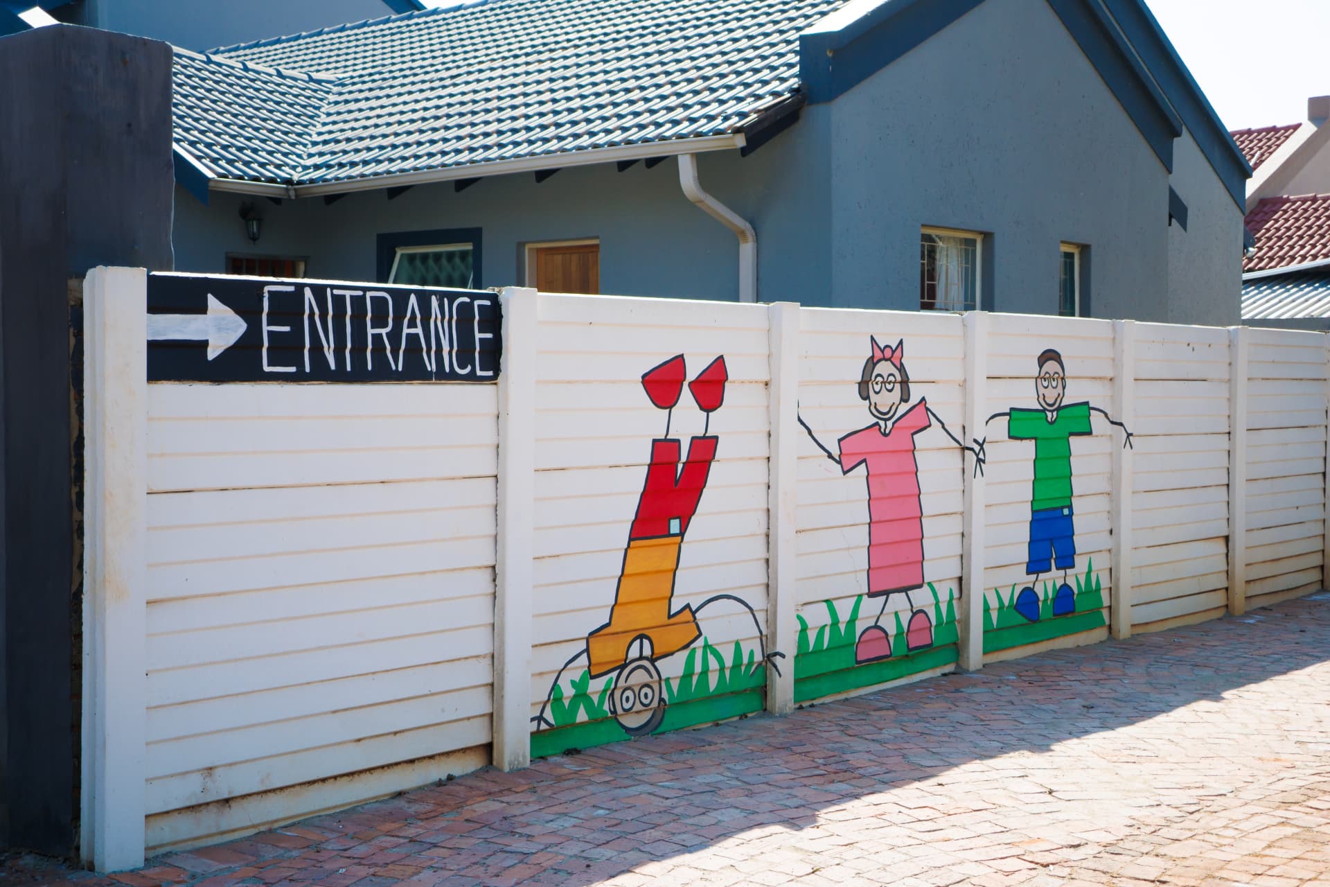 Painted entrance wall with children and an entrance sign