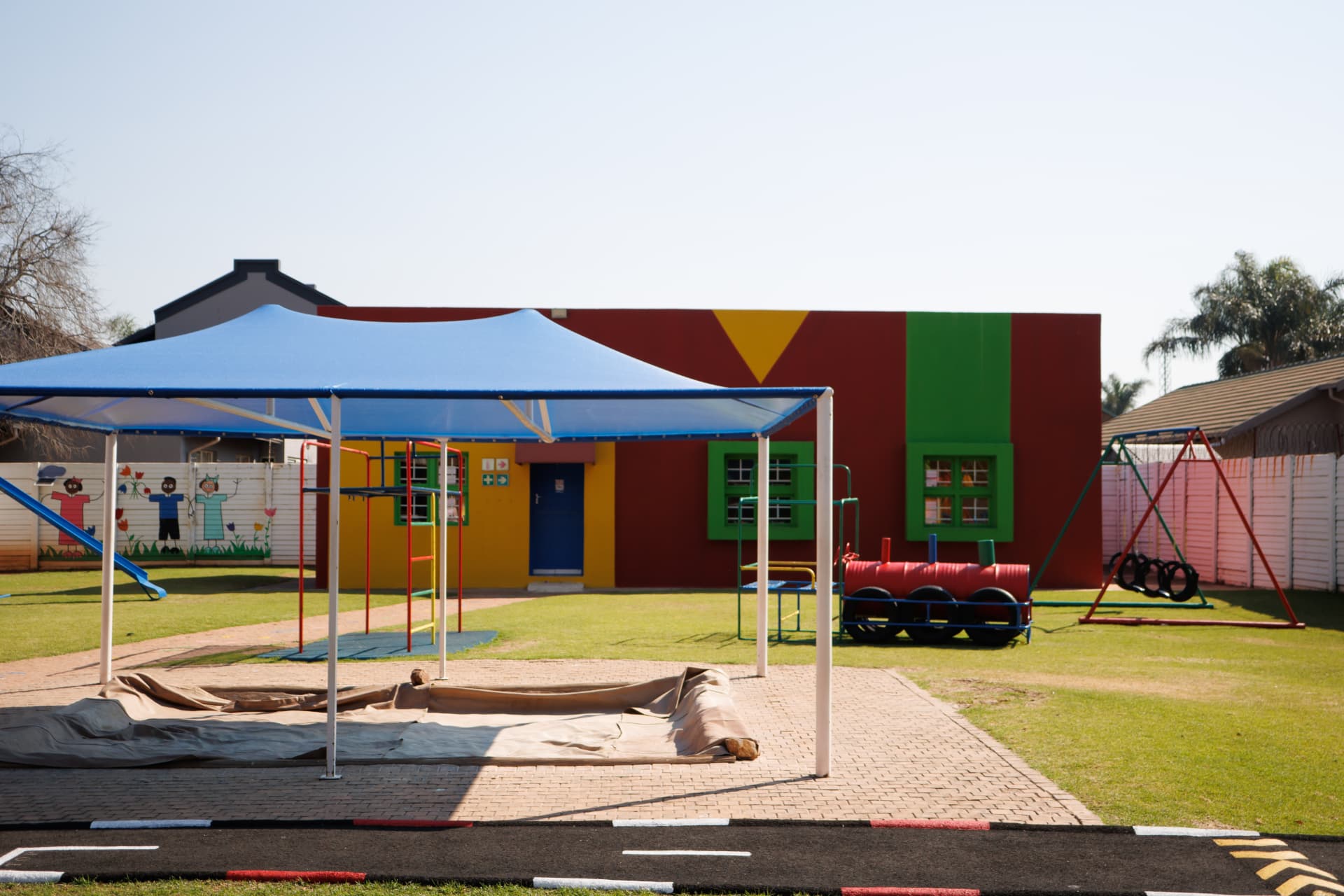 Shaded sandpit and play area in front of the colourful school building