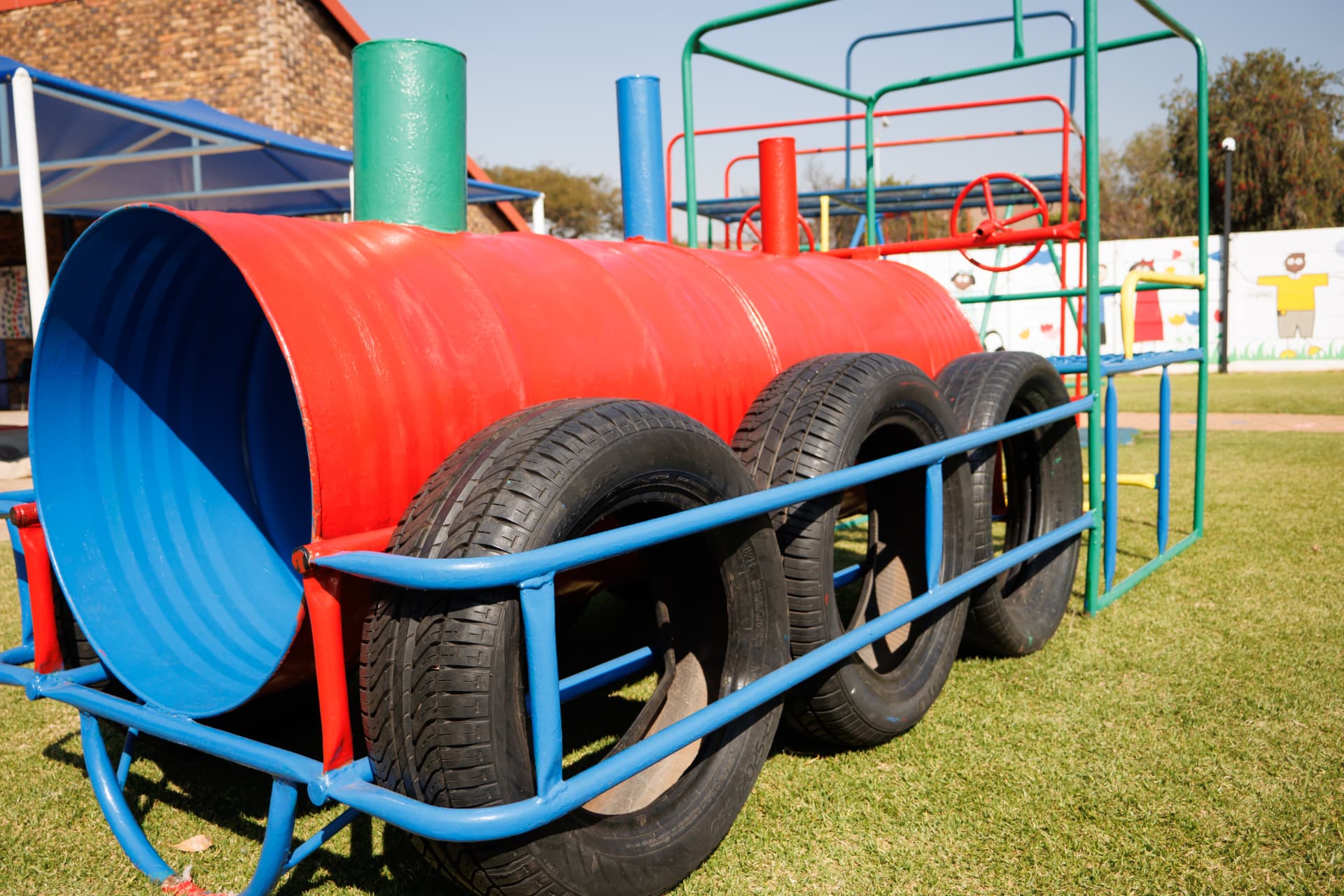 Play train made from a red drum and tyres on the grass