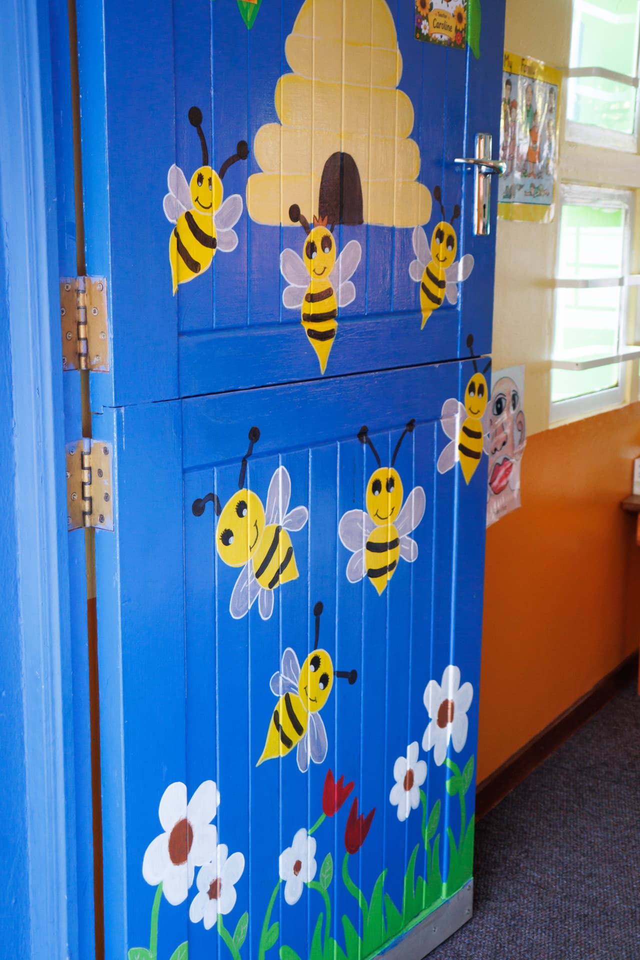 Blue classroom door hand-painted with bees and a beehive